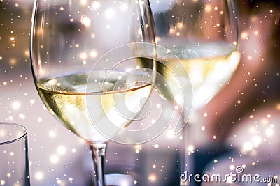 Winter holiday glasses of white wine and glowing snow on background, Christmas time romance Stock Photo