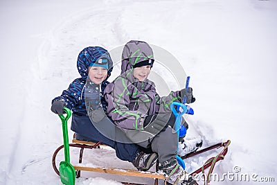 Winter holidays fun. Two boys have together sliding on a pleasant day Stock Photo