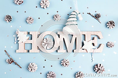 Winter holidays word home with snow painted pine cones and stars on blue background. Stock Photo