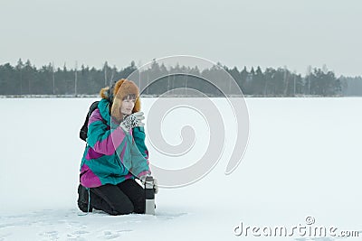 Winter hunkering hiker woman drinking hot tea from vacuum flask metal cup Stock Photo