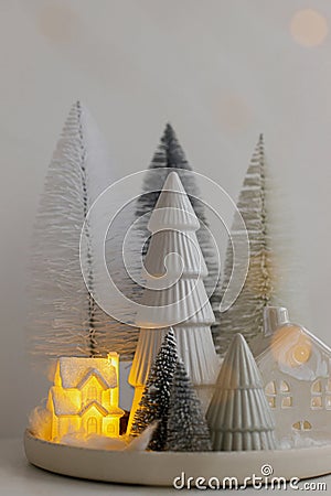 Winter hygge, cozy christmas magical scene, miniature snowy village with lights. Stylish little Christmas trees and house on white Stock Photo