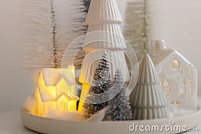 Winter hygge, cozy christmas magical scene, miniature snowy village with lights. Stylish little Christmas trees and house on white Stock Photo