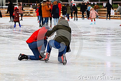 Winter ice rink. A group of People ride fun and fall on the ice. Active family sport during children`s Christmas winter break. Editorial Stock Photo