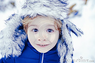 Winter kid excited face close up. Happy winter time. Happy child playing with snow on a snowy winter walk. Stock Photo