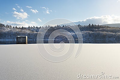 Winter landscape, lake with a dam in the foreground, against the forest and blue cloudy sky, beautiful nature, Western Ukraine Stock Photo