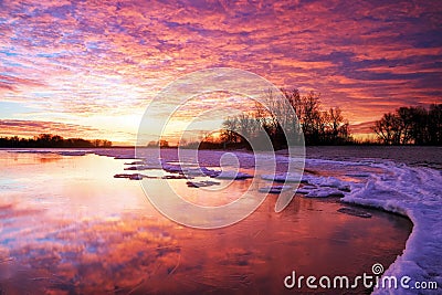 Winter landscape with lake and sunset fiery sky. Stock Photo