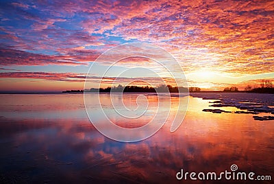 Winter landscape with lake and sunset fiery sky. Stock Photo