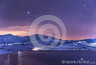 Winter landscape. Panoramic view on the lake and mountains peaks snow-covered at the starry night. Stock Photo