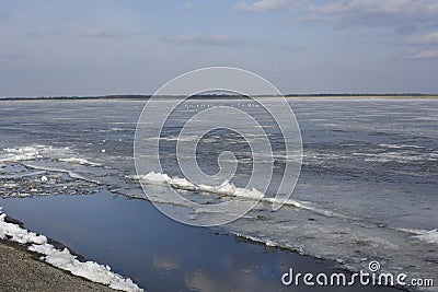 Winter landscape with partly frozen river. Ice floes float on the blue surface. Ice drift. Global warming concept. Stock Photo