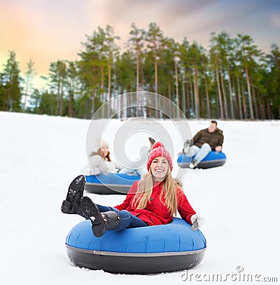 Happy friends sliding down hill on snow tubes Stock Photo