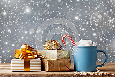 Winter lifestyle with cup of hot cocoa with marshmallows and Christmas gift or present boxes on wooden background. Snow effect Stock Photo