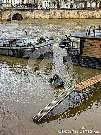 Man struggles to propel rowboat from houseboat on flooded Seine River, winter 2018, Paris, France Editorial Stock Photo