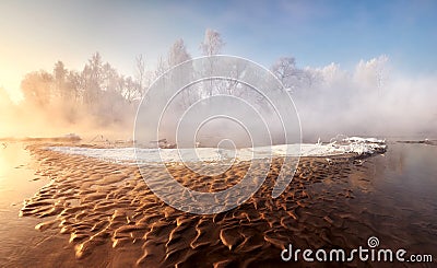 Winter morning frosty scenery with a small forest river and brown sandy shallows, similar to lava. Stock Photo