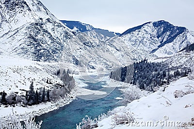 Winter mountain breathtaking landscape, turquoise river running between the mountain slopes, white snow, spruce forest Stock Photo