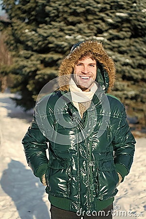 Winter outfit. Man unshaven wear warm jacket with fur snowy nature background. Guy wear winter jacket with furry hood Stock Photo