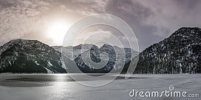 winter panorama of frozen lake plansee amidst alpine mountains Stock Photo