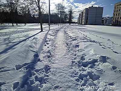 winter path in the city behind multi-storey buildings in the sunny daytime. Stock Photo