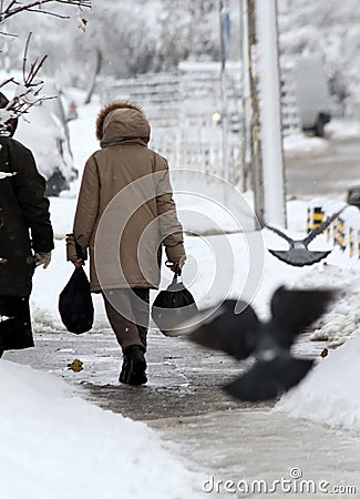 Winter. People walk on a very snowy sidewalk. People step on an snow-stray pathway. Icy sidewalk. Ice on sidewalks Editorial Stock Photo
