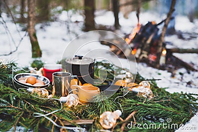 Winter picnic in the snow near by campfire. Christmas garlands on fir branches Stock Photo