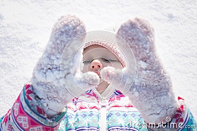 Little cheerful girl, 7-8 years old, in bright winter overalls, sits on the snow Stock Photo