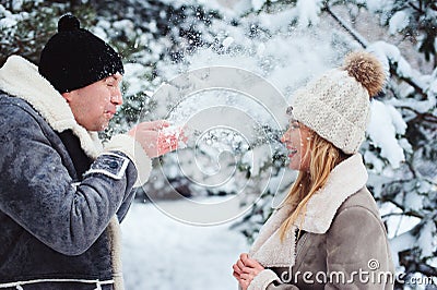 winter portrait of happy couple playing, blowing snow and spending good day outdoor in snowy forest Stock Photo