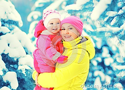 Winter portrait happy smiling mother holds baby on hands over snowy christmas tree Stock Photo