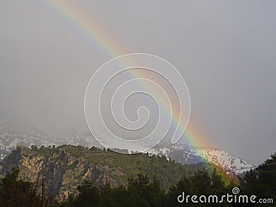 Winter rainbow in the forest and snowy mountains Dirfys on the island of Evia in Greece Stock Photo