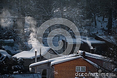 winter scenery with smoke coming from house chimneys Stock Photo
