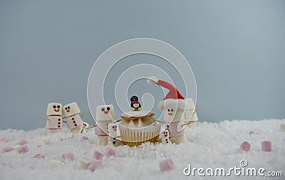 Christmas food photography using marshmallows shaped as snowman and standing in snow with cream sponge fairy cake Stock Photo