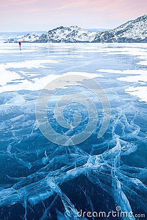 Winter Siberian landscape. Mountains and clear ice with cracks on Lake Baikal. Stock Photo