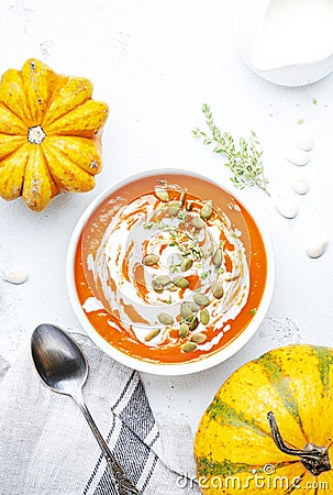 Winter slow food. Pumpkin carrot soup with cream, seeds and thyme.. Healthy diet food. White soup bowl on gray table background. Stock Photo