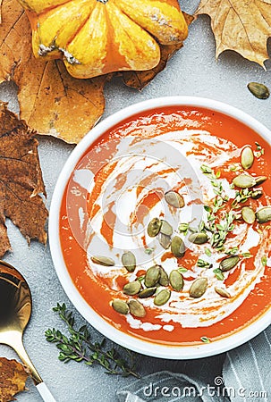 Winter slow food. Pumpkin soup puree with seeds, coconut cream and thyme.. Healthy vegan vegetarian food. White soup bowl on gray Stock Photo