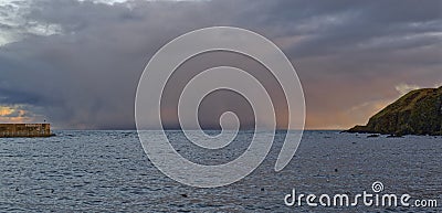 A Winter Storm outside Stonehaven Harbours Breakwater and Headland, catching the light of the setting sun Stock Photo