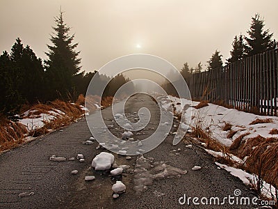 Winter stormy weather in mountains, dark snowy clouds, cold snow in the sky. The road covered by snow and ice. Slipper asphalt Stock Photo