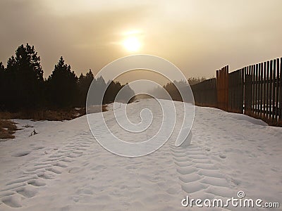 Winter stormy weather in mountains, dark snowy clouds, cold snow in the sky. The road covered by snow and ice. Slipper asphalt Stock Photo