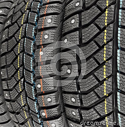 Winter studded tire. Winter car tires background. Tire stack background. Tyre protector close up. Square powerful spikes. Black Stock Photo