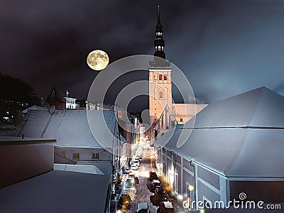  Tallinn old town blue sky and full moon snow on medieval tower roof night street blurred light panorama travel to Estonia Stock Photo