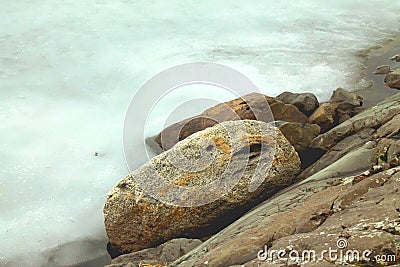 Winter view to the snowy ice and rocks on the shores of icy lake Stock Photo