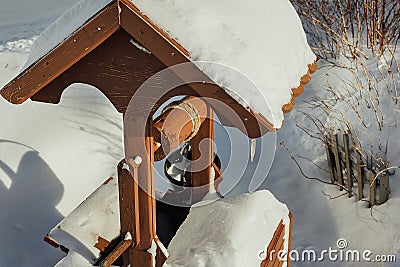 Winter village landscape. A wooden well and a fence in snowdrifts. It& x27;s a sunny, frosty day Stock Photo