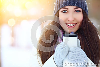 Winter young woman portrait. Beauty Joyful Model Girl holding thermocup with hot tea and smiling, having fun in winter Stock Photo