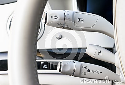 Wipers switch control. White leather Modern car interior detail. Cruise control buttons on modern car and speed limitation. Stock Photo