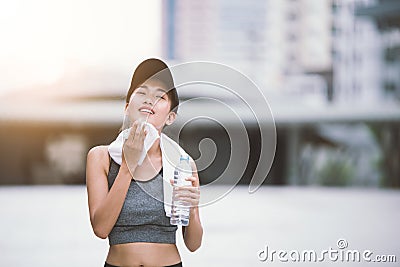 Wiping sweat Thirsty exercising female drinking fresh water after training Stock Photo