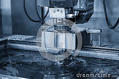 The Wire EDM machine cutting the die parts with liquid coolant. Stock Photo