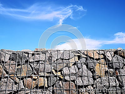 Wire and stone fence. decorative building made of stone Gabion Stock Photo