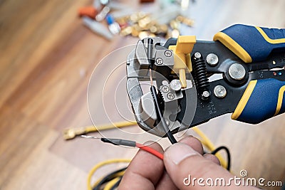 Wire strippers or cable strippers tool . Electrician holding cable strippers tool to remove insulation from electrical wires.Work Stock Photo