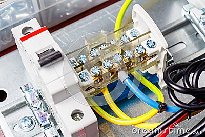 Wire terminal and automatic circuit breaker with connected colored wires installed on electrical panel. Close-up view Stock Photo