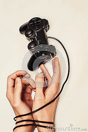 Wired hands with joypad close up meaning videogame addiction Stock Photo