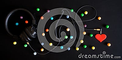 Wired headphones, multicolored balls and a red heart on a black background. Audiophilia and a variety of emotions evoked by music Stock Photo