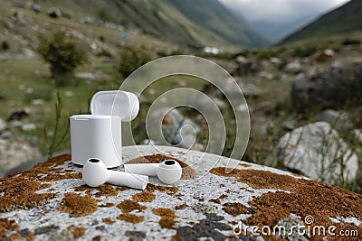 Wireless earphones, earbuds on a nature stone background Stock Photo