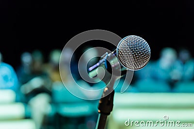 Wireless microphone on the stand. Blurred background. People in the audience. Show on stage in the theater or concert hall Stock Photo
